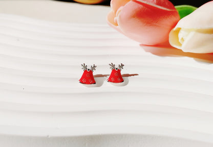 sterling silver Christmas Bell Stud Earrings Featuring red bells with cute antlers, displayed on a white textured background with pink tulips nearby.