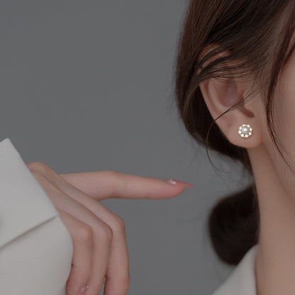 Woman wearing Pearl and Cubic Zirconia Stud Earrings with a white pearl center surrounded by sparkling stones in a gold-plated setting.