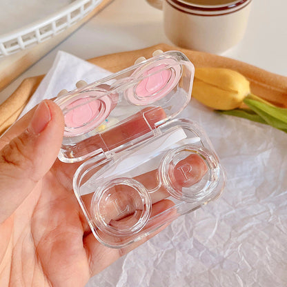 Close up of an opened travel lens case including a double box tweezers, and a wearing rod